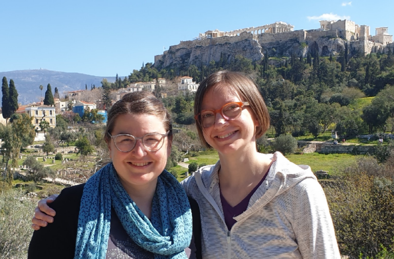 Katrin und Marianne sind auf dem Foto zu sehen, im Hintergrund die Akropolis in Athen. Anlass war das Kritzelspiele Mastermind in Athen, März 2023